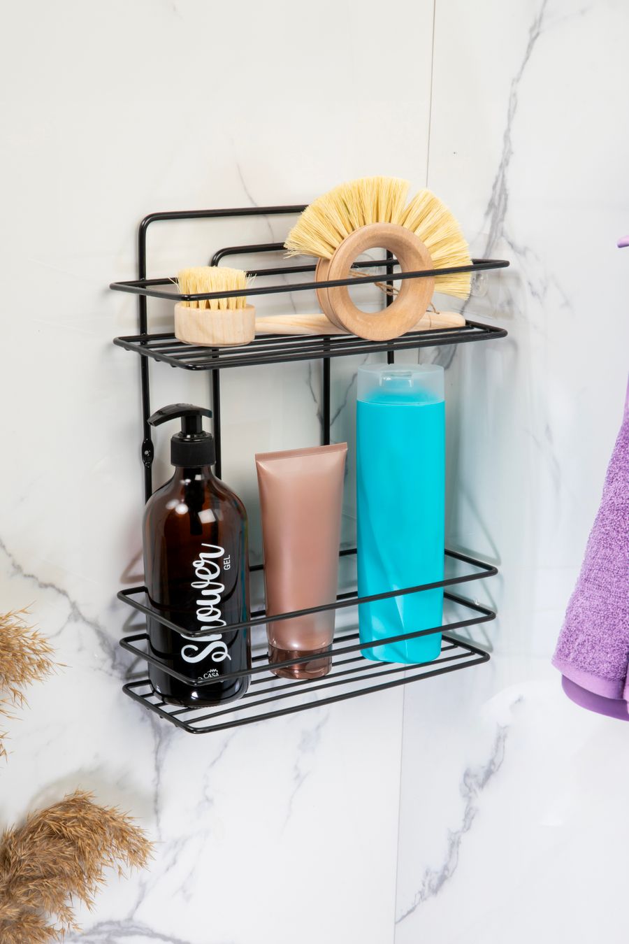 Black wall-mounted bathroom rack holding shampoo, soap and brushes against marble tiles