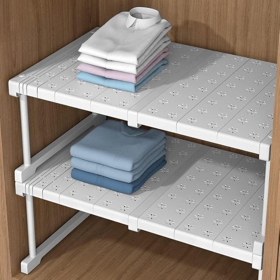 Two wardrobe shelf dividers holding folded shirts inside a wooden wardrobe